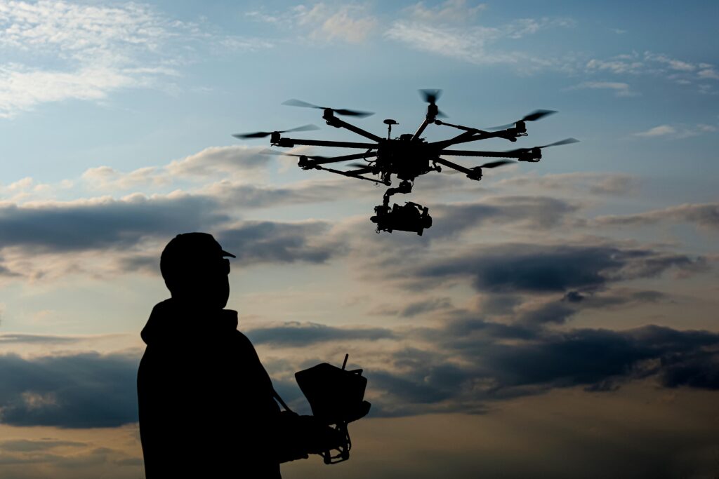 Drone pilot silhouetted against the sky flying a cinema drone