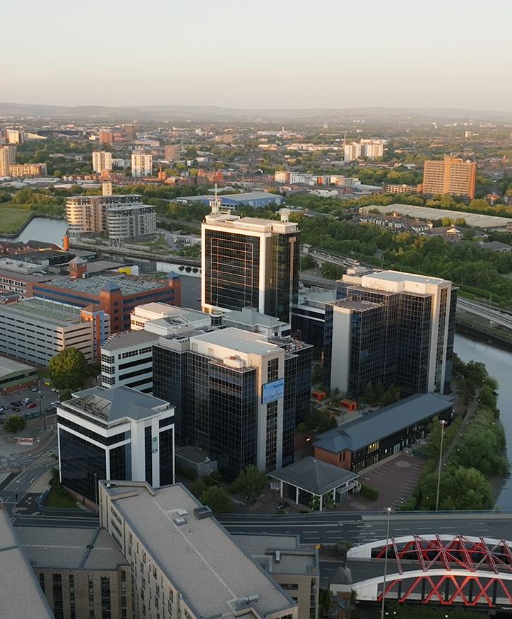 A aerial photo of Exhange Quays taken at sunset. Manchester can be seen behind along with canals and bridges