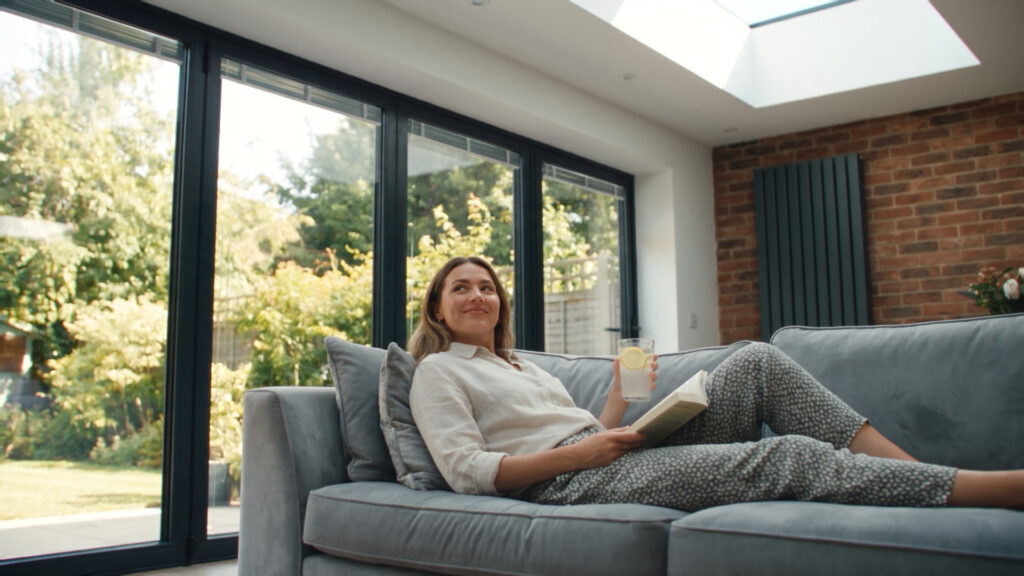 Woman relaxing on a sofa by a window – ClimaGuard 365 AI advert for Morley Glass